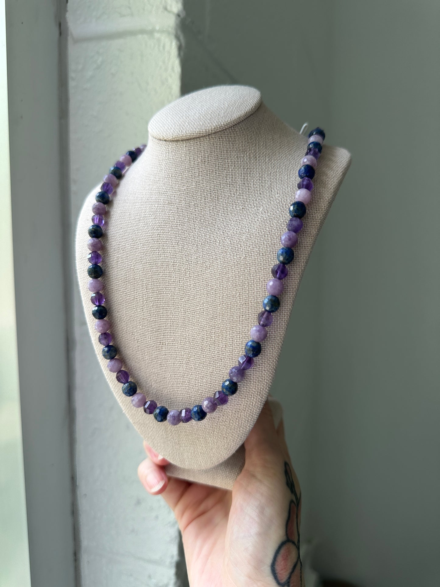 Necklace with purple and blue beads on a display stand.