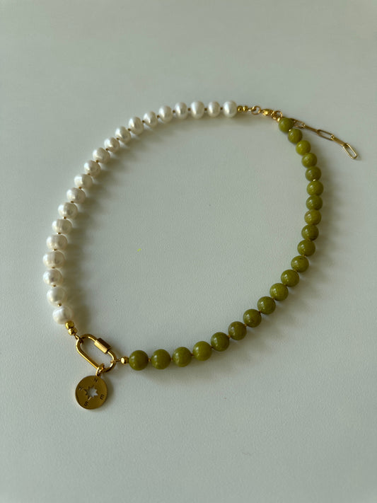 Beaded necklace with jade and pearls and a gold clasp on a light gray background