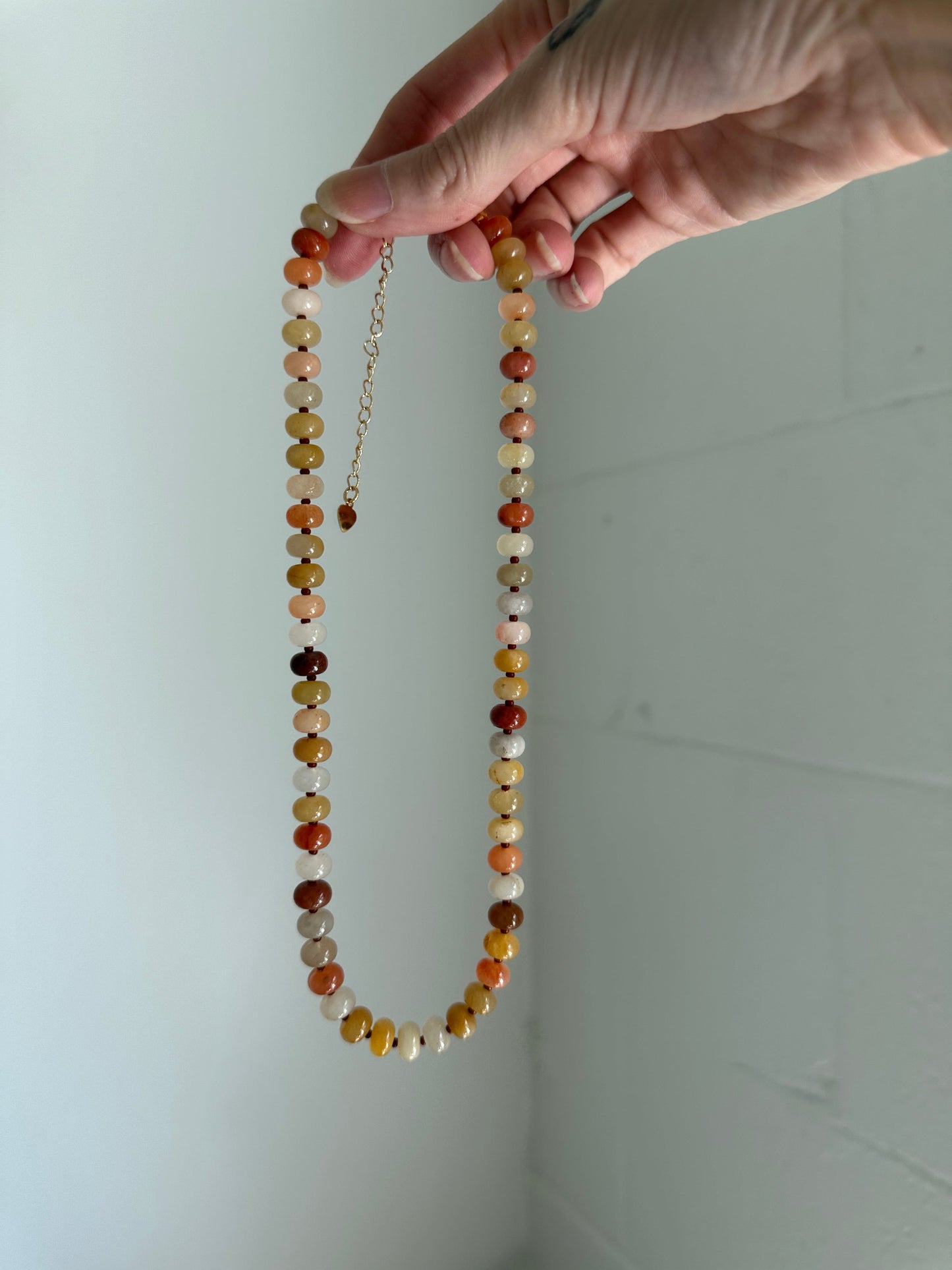 Beaded necklace held by a hand against a white background